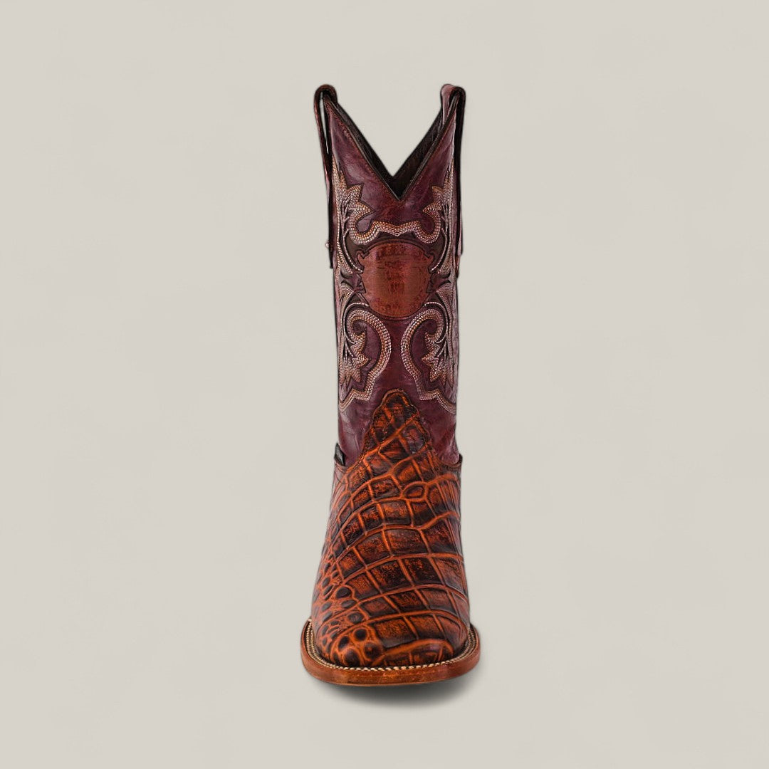 The Jonh - Cogñac - Square Toe boot from the Last Call collection is shown front-facing, with a brown and tan crocodile-textured foot and an ornate, reddish-brown shaft featuring decorative stitching on a plain background.