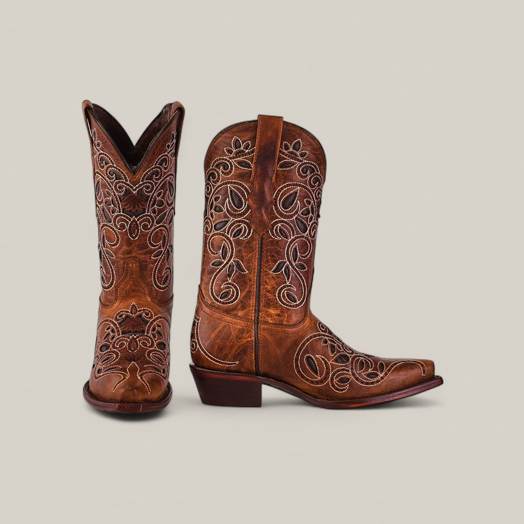 The Gina - Brown - Snip Toe boots feature premium cowhide leather in brown with detailed white embroidery. Displayed side by side on a light background, one boot stands upright while the other is angled to highlight its features.