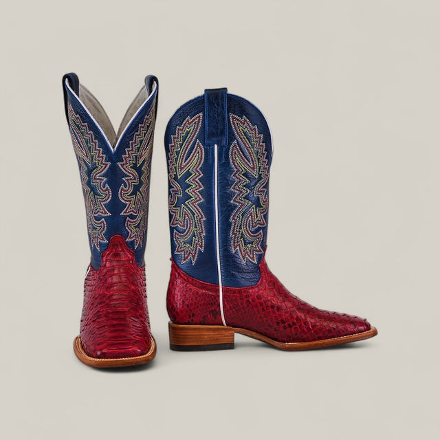 The Exotic Python - Ruby / Blue - Square Toe boots feature red python leather on the foot and blue shafts with vibrant, intricate stitching, displayed against a plain light background.