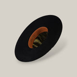 The 10X Grizzly - Tacchino is a black felt open crown hat, shown from above to display its tan leather inner band and green and gold paisley lining, set against a plain beige background.