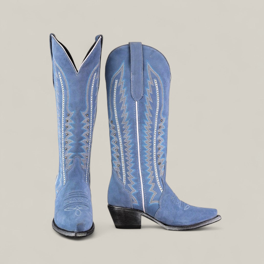 The Elizabeth Light Blue - Tall Shaft Snip Toe boots feature blue suede, decorative white stitching, pointed toes, and angled heels. Displayed against a plain light gray background.