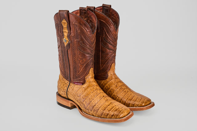 The Exotic Caiman Belly - Camel - Square Toe boots feature a brown and tan caiman belly with detailed upper shaft stitching and a textured, crocodile-patterned lower, displayed on a plain light gray background.