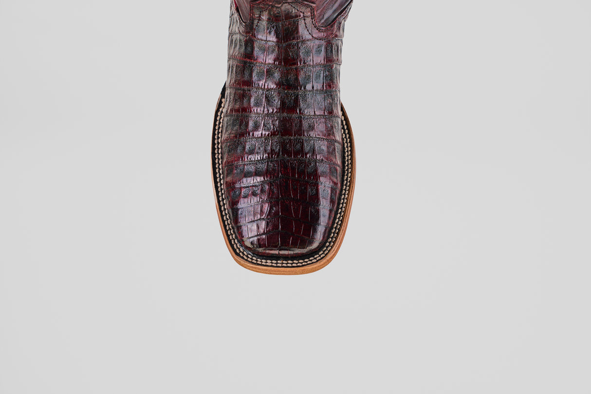 A close-up of the toe of the Exotic Caiman Belly - Black Cherry - Square Toe boot, highlighting its handcrafted crocodile-patterned finish, square shape, and rich detailed stitching—showcasing true luxury.