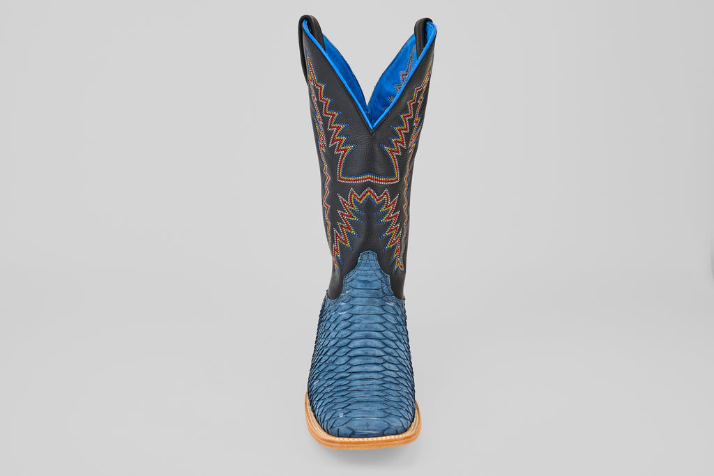 A single Kingsley - Blue Jeans - Square Toe mens boot with a blue textured lower, black upper featuring red and yellow stitching, blue lining, and light brown sole is shown against a plain gray background.