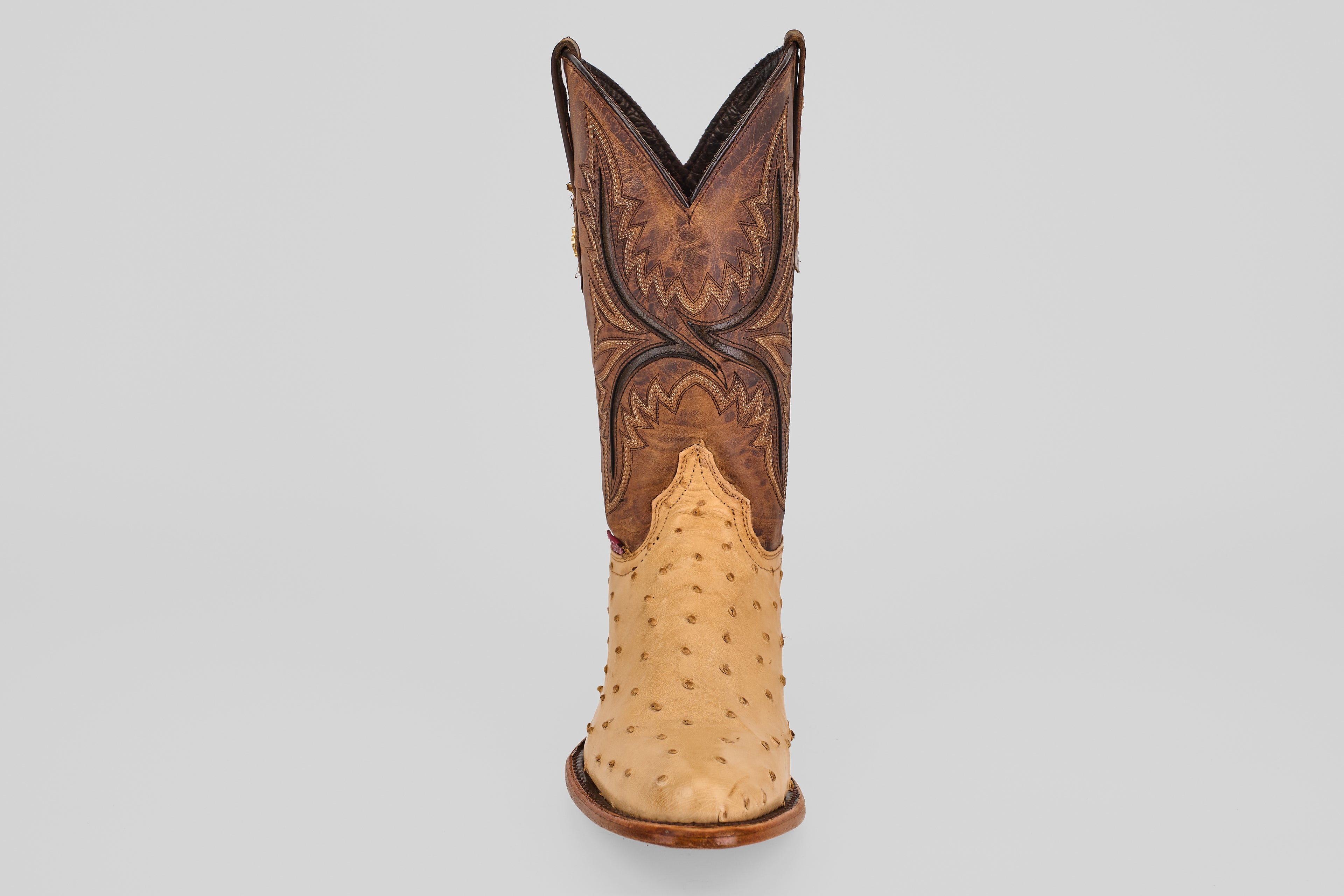 The Exotic Full Quilt Ostrich - Orix - Round Toe boot stands upright, featuring a tan quilted ostrich lower and a dark brown, ornately stitched upper, handcrafted in classic Western style on a plain light gray background.