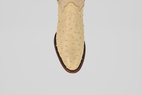 A top-down view of the Exotic Full Quilt Ostrich - Bone - Round Toe cowboy boot’s toe, featuring beige genuine ostrich leather and a brown sole, showcases its luxurious texture and craftsmanship against a white background.