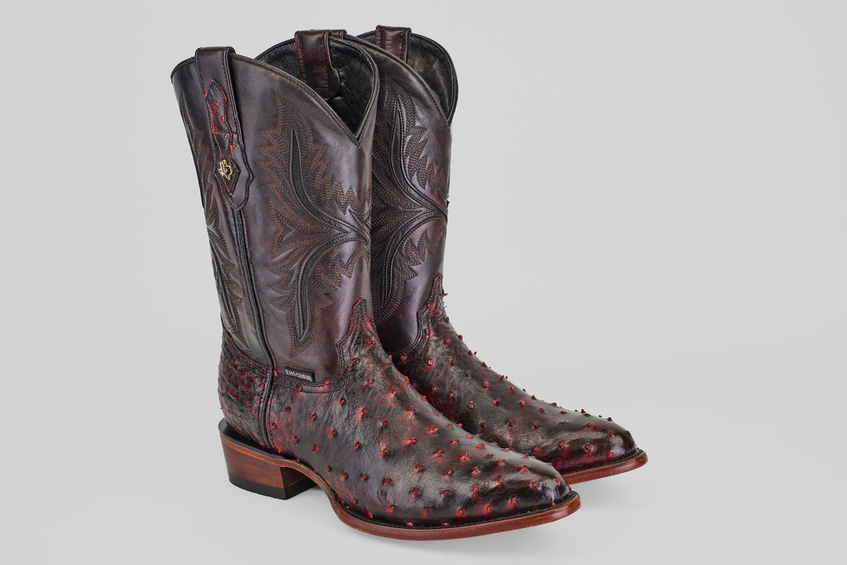 A pair of Exotic Full Quilt Ostrich - Black Cherry - Round Toe cowboy boots with decorative shaft stitching and textured black cherry accents, displayed on a plain light gray background.