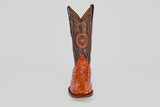 The Austin - Brandy - Square Toe features a single brown cowboy boot with a textured Avestruz Brandy leather foot, dark shaft, and circular star emblem on the front, shown against a plain light background.