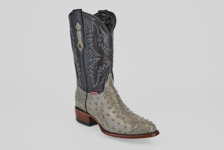 The Austin - Oxford - Round Toe men's cowboy boot features a gray ostrich leather foot, a black leather shaft with decorative stitching, and a brown wooden heel, displayed on a plain light background.