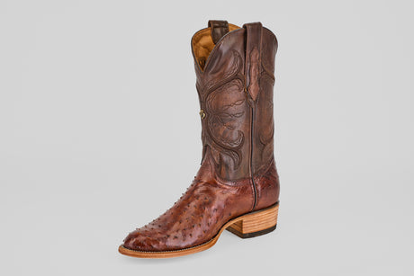 A single Austin - Tabaco - Roper Toe men’s cowboy boot in brown ostrich leather with a roper toe, decorative shaft stitching, and a wooden heel is shown on a plain light gray background.