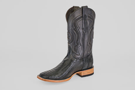 The Austin Leg - Black - Square Toe is a single black cowboy boot with decorative stitching, a square toe, and a light brown wooden heel, displayed on a plain light gray background. Ideal for fans of classic cowboy boot style.