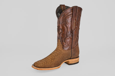 The Tanner - Tamarindo - Square Toe cowboy boot is brown with a textured, scaly lower section, a smooth, stitched upper shaft, and a low wooden heel, shown against a plain light gray background.