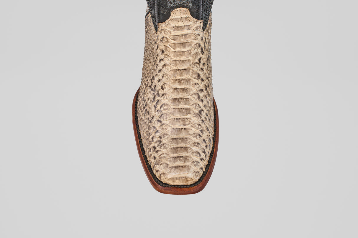 A close-up, top-down view of the Tanner - Natural - Narrow Square Toe boot displays its light python-textured snakeskin and dark upper, highlighting distinct Western style against a plain white background.