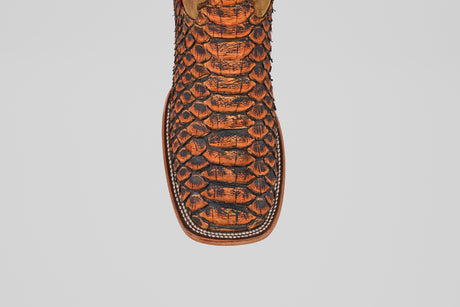 A close-up of the Tanner Jumbo – Chestnut – Square Toe boot, featuring a premium orange and black python snakeskin texture on the toe, showcased against a plain white background.