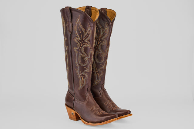 A pair of Allison Dark Moka - Tall Shaft - Snip Toe women's cowboy boots in dark mocha leather with intricate stitching, angled heels, and snip toes stand upright on a light gray background.