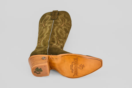 The Allison Agave - Tall Shaft - Snip Toe women’s cowboy boot, shown in brown suede, features a decorative logo on the heel, metal tack detail, intricate stitching, and a sole stamped with Texas Country.