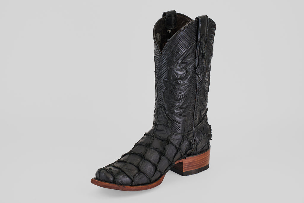 The Conor - Matte Black - Narrow Square Toe boot features a textured, scale-like pattern, decorative stitching on the shaft, and a brown wooden heel and sole. Photographed against a plain light gray background.