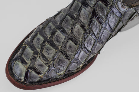 Close-up of the Conor - Charcoal - Roper Toe, a men's cowboy boot featuring textured, glossy reptile skin with distinct raised scales and a brown leather sole—an elegant update to classic Western style.