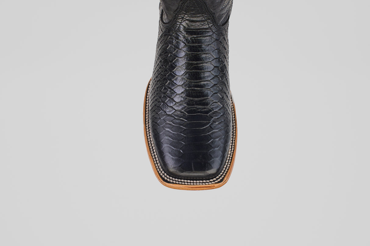 Close-up top view of the Python Black - Embossed Leather - Square Toe (E425) cowboy boot, featuring a shiny textured snakeskin pattern and light brown sole, stylishly displayed against a plain white background.