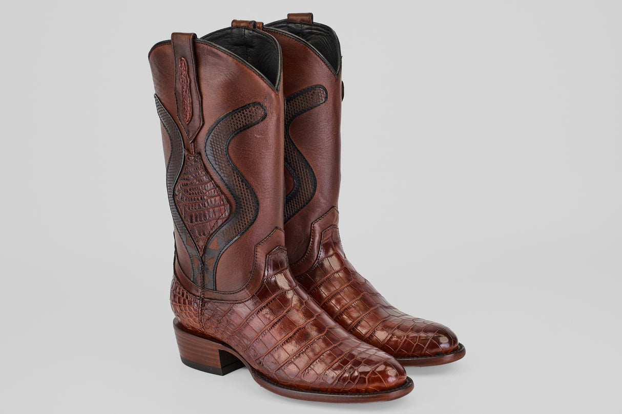 The James Platimun - Dark Cogñac boots feature a roper toe (Diamond), textured alligator-inspired foot, decorative stitching on the shaft, brown color, low heel, and high-calf men's western style.