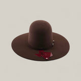 The 4X - Chocolate - TC Hats is a wide-brimmed, dark brown felt Western hat in Texana style, shown against a plain light background with a Texas-shaped tag hanging from its decorative band.
