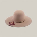 The 4X - Belly - TC Hats is a wide-brimmed, light pink felt Western hat with a thin matching band and gold buckle, maroon tag on the band, and a shapeable crown, shown against a plain light background.