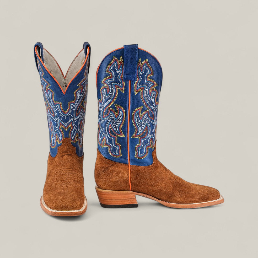 The Buck - Camel - Square Toe mens boots feature brown suede feet and blue leather shafts with colorful embroidered patterns; one boot stands upright while the other lies on its side against a neutral background.