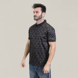 A man with short dark hair and a beard wears the Mens Modern Fit Stretch Cotton Black Polo with Aztec Print (AZP10859) and blue jeans, standing against a plain light background. He faces slightly left, his expression neutral.