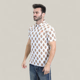 A man with short dark hair and a beard wears the Mens Performance Fabric Modern Fit Stretch Aztec Print White Polo - PGP10870 and blue jeans, standing against a plain light beige background.