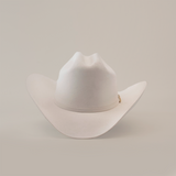 The 6X Real White is a luxury Western cowboy hat with a wide brim and creased crown, handcrafted by artisans from fur felt. It is elegantly displayed against a plain white background.