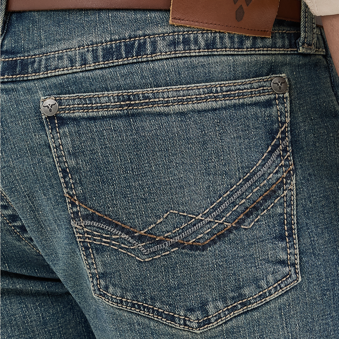 Close-up of the Wrangler Mens 20X Extreme Relaxed Fit Jeans - 1044MWXMA shows a back pocket with decorative stitching, brown leather belt at the waist, and a branded leather patch. These premium denim jeans boast a slightly faded look, offering relaxed fit and ultimate comfort.