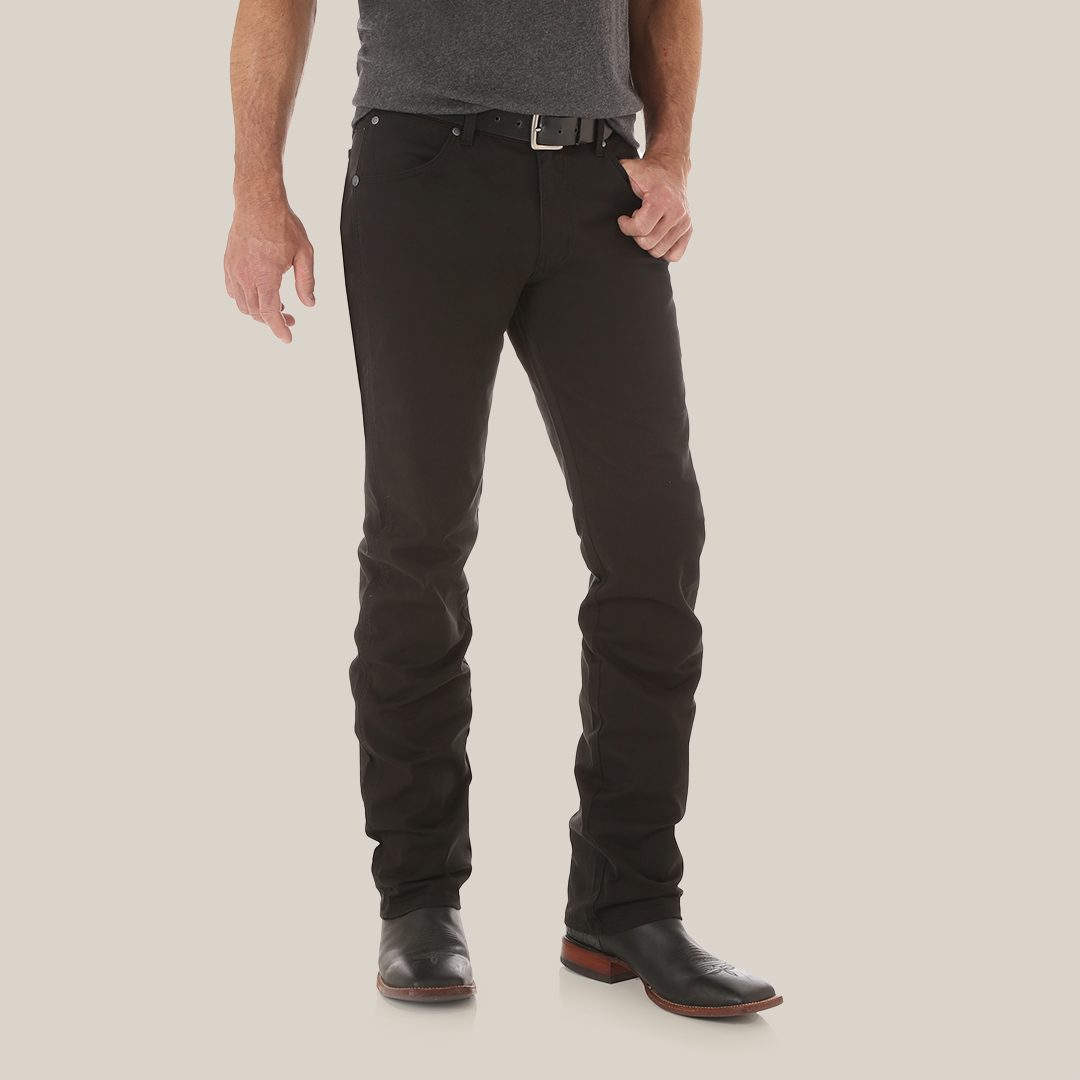 A person wears Mens Wrangler Retro Slim Fit Straight Leg Pants (88MWZBK) with a black belt and dark shoes. Their partly visible upper body features a dark gray shirt. The premium denim stands out against the white background.