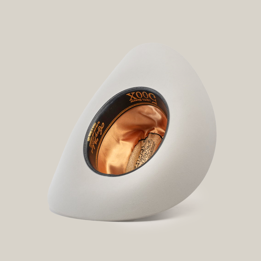 A light grey, asymmetrical hat crafted from luxurious belly beaver fur features a rounded, hollow center lined with orange satin. Inside this exquisite Western headwear, a black label with gold lettering proudly displays 500X Superior Platinum.