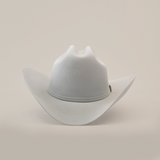 The 100X Independencia Platinum cowboy hat, in light gray, captures the El Presidente style with its wide brim and slightly curved crown, elegantly resting on a smooth surface.
