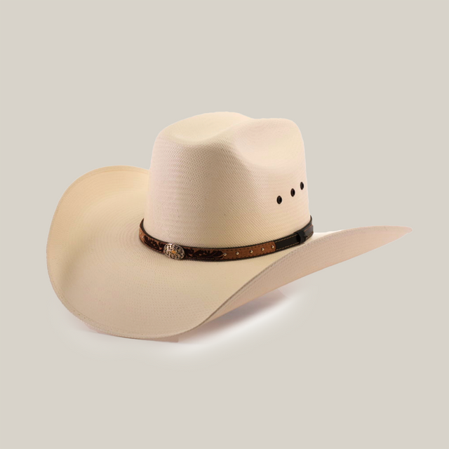 The 500X Bull Straw Hat is a beige cowboy hat offering Western elegance with a wide brim and a genuine leather band featuring decorative studs. The crown has a stylish dent, and the band includes a small metal embellishment on the side.