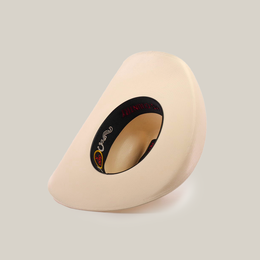 The 500X Bull Straw Hats beige, wide brim showcases Western elegance. Displayed tilted on its side, it highlights a black genuine leather band inside, with the brand logo proudly exhibited within the crown.