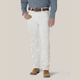 A person wearing a blue button-up shirt, Wrangler Cowboy Cut Slim Fit Jeans (0936WHI), and a brown leather belt is grounded in brown suede shoes. The iconic Wrangler patch enhances the look against the plain white background.