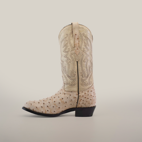 The Karoo Ostrich Print Bone - Round Toe is a single, light-colored cowboy boot with ornate stitching and a textured ostrich print surface, featuring a low heel and leather sole on a plain white background.