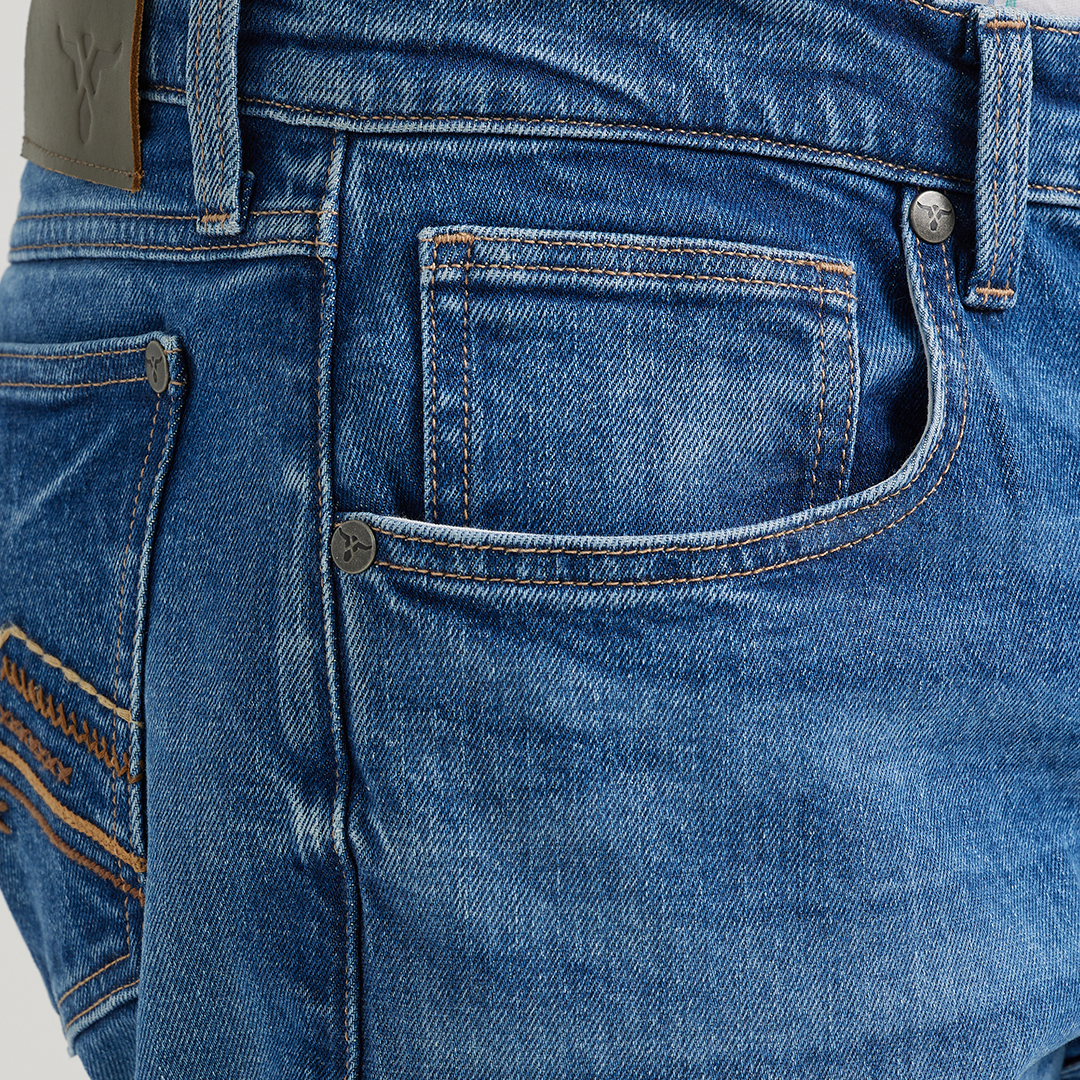 A person is wearing Wrangler 20x Mens Medium Wash Backwater Vintage Bootcut Stretch Denim Jeans, showcasing the small pocket and brown leather patch. Their plaid shirt with striped patterns pairs perfectly, adding a vintage denim vibe.