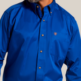 A person smiling in a Solid Twill Classic Fit Shirt Blue - 10006660, made of 100% cotton twill, with brown buttons and a small emblem on the pocket. The smart collar adds to its charm. Image highlights the upper chest and part of the face.