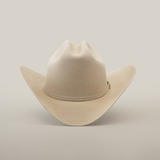 The 6X Real Belly, a premium beige fur cowboy hat, sports a wide brim and pinched crown with subtle decorative stitching, set against a plain white background.